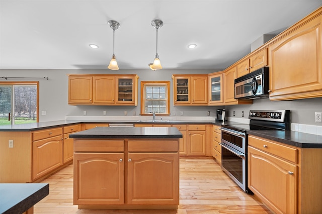 kitchen featuring dark countertops, a sink, light wood-style floors, range with two ovens, and a kitchen island