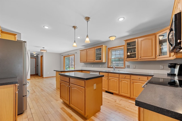 kitchen featuring dark countertops, black microwave, a sink, a center island, and freestanding refrigerator
