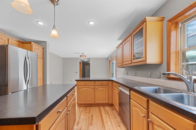 kitchen featuring a peninsula, dark countertops, appliances with stainless steel finishes, and light wood-style floors