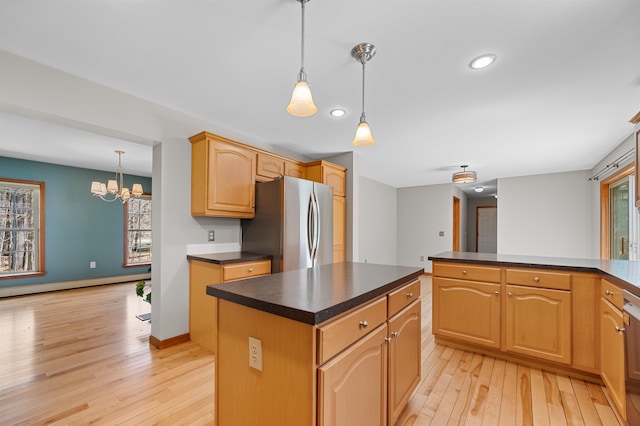 kitchen featuring dark countertops, plenty of natural light, freestanding refrigerator, and light wood-style flooring