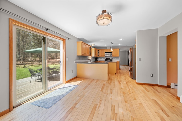 kitchen with appliances with stainless steel finishes, baseboards, a baseboard heating unit, a peninsula, and light wood-style floors