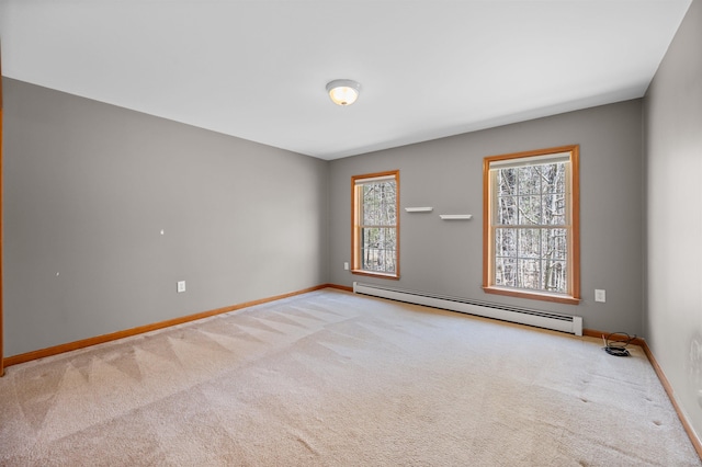 carpeted spare room featuring baseboards, a baseboard heating unit, and a wealth of natural light