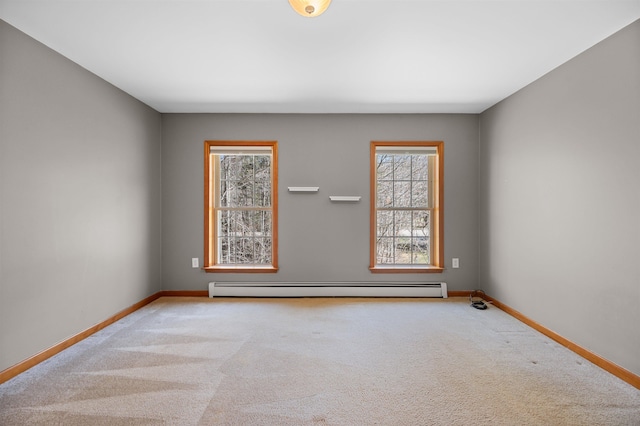 carpeted spare room featuring baseboards, baseboard heating, and a wealth of natural light