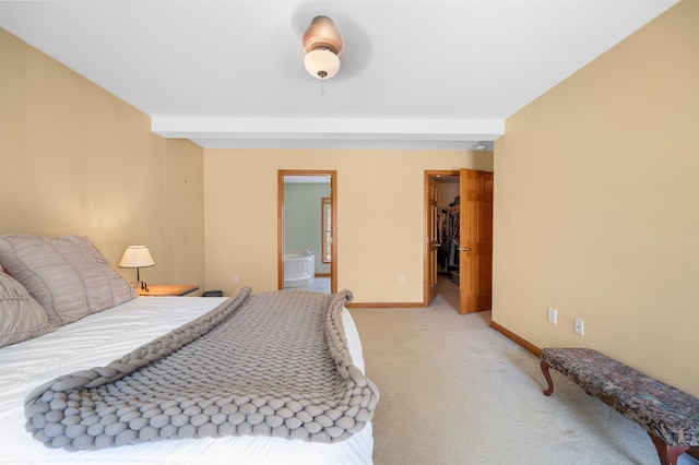 bedroom featuring light colored carpet, connected bathroom, baseboards, and a spacious closet
