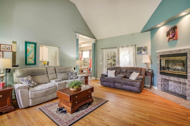 living room with high vaulted ceiling, baseboards, a fireplace, and wood finished floors