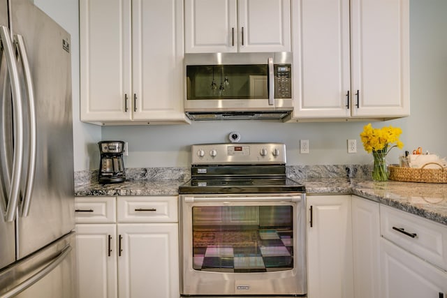 kitchen featuring appliances with stainless steel finishes, white cabinets, and light stone countertops