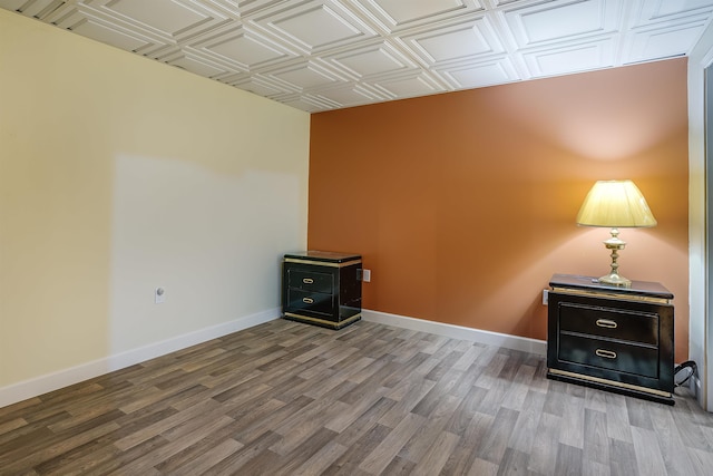 empty room featuring an ornate ceiling, baseboards, and wood finished floors