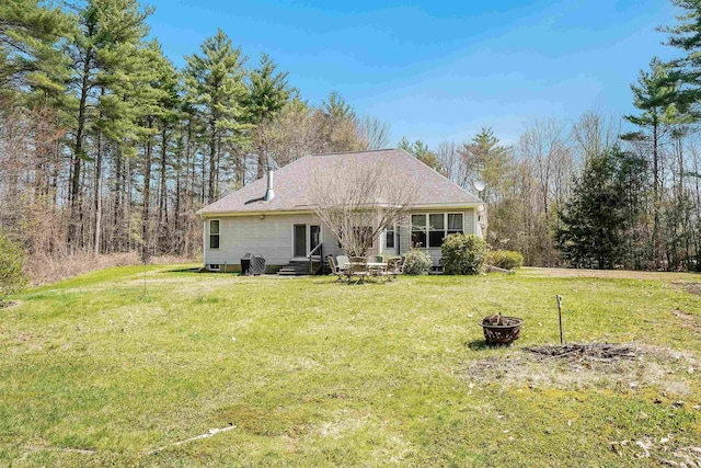 back of property featuring entry steps, a yard, and an outdoor fire pit