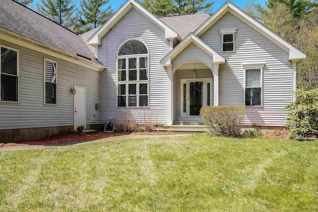 view of front of property featuring roof with shingles and a front lawn