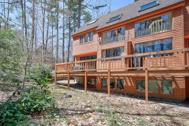 rear view of house with roof with shingles and a wooden deck