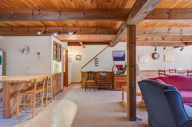 carpeted dining area with track lighting, beam ceiling, and wooden ceiling