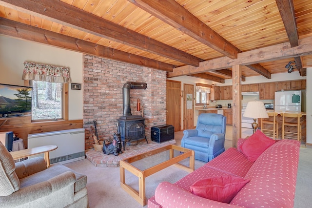 living room featuring light colored carpet, wooden ceiling, beam ceiling, and a wood stove