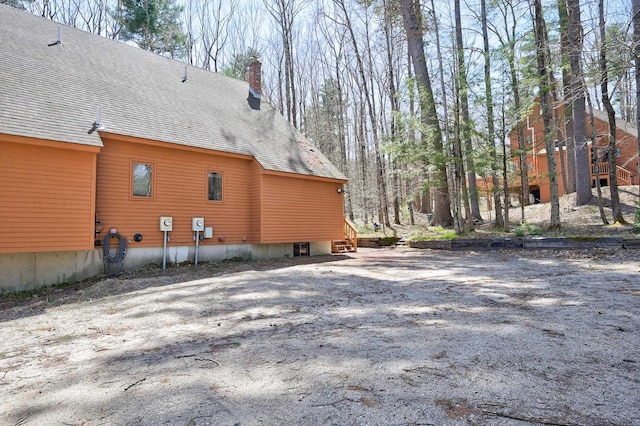 view of side of property with a shingled roof and a chimney