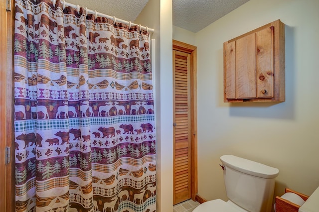 bathroom with a shower with curtain, toilet, and a textured ceiling