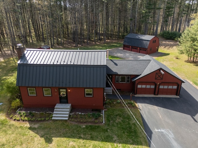 view of front facade featuring a standing seam roof, an outbuilding, metal roof, and aphalt driveway