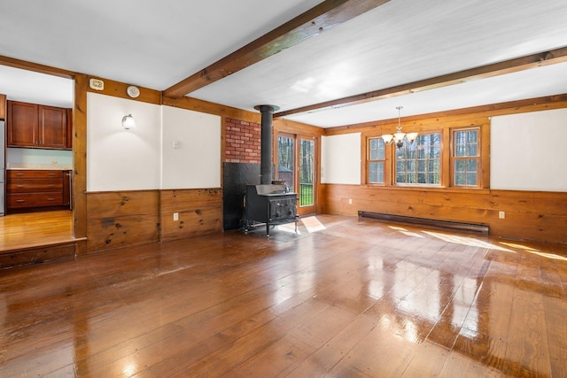 living area with a wood stove, wood walls, a baseboard radiator, beamed ceiling, and hardwood / wood-style floors