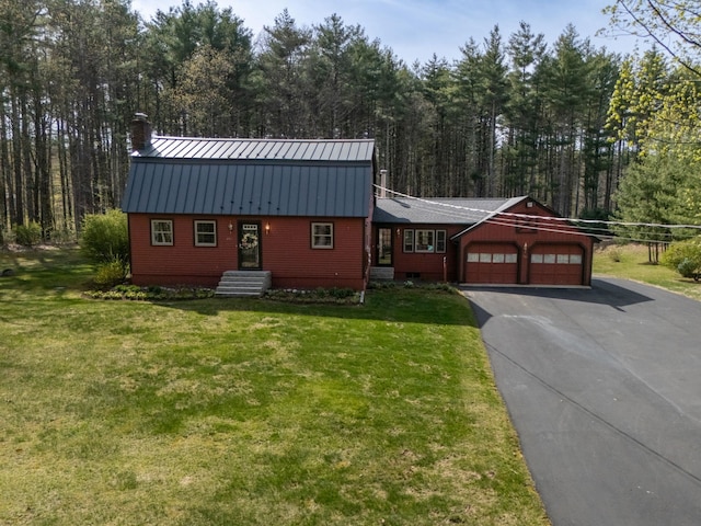 colonial inspired home with an attached garage, aphalt driveway, metal roof, and a front lawn