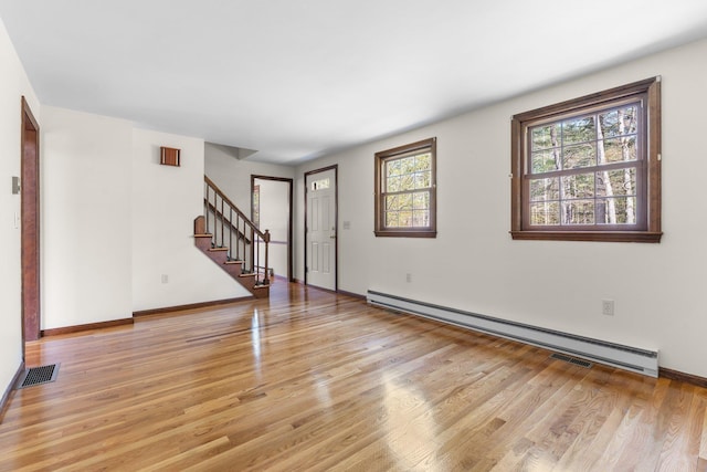 unfurnished living room with visible vents, baseboards, stairway, a baseboard radiator, and light wood-style flooring