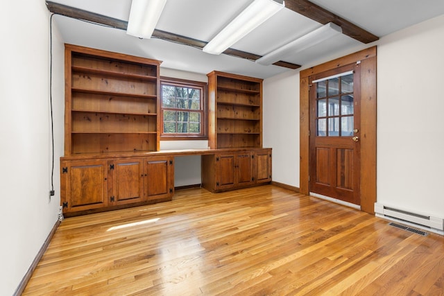 unfurnished office featuring light wood finished floors, built in desk, and visible vents