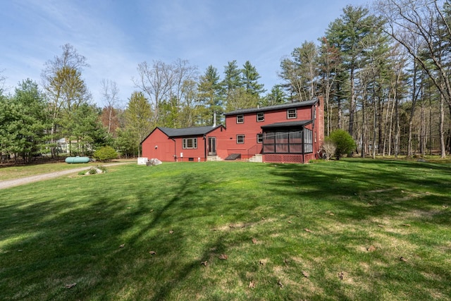 rear view of property with a lawn, a chimney, and a sunroom
