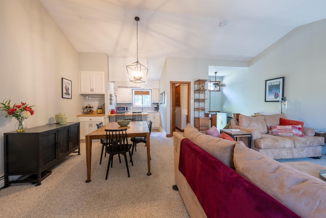 living room with an inviting chandelier, light carpet, and vaulted ceiling