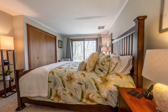 carpeted bedroom featuring visible vents, a textured ceiling, and a closet