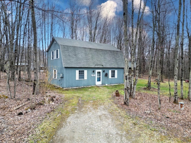 dutch colonial with a gambrel roof, an outbuilding, driveway, and a shingled roof