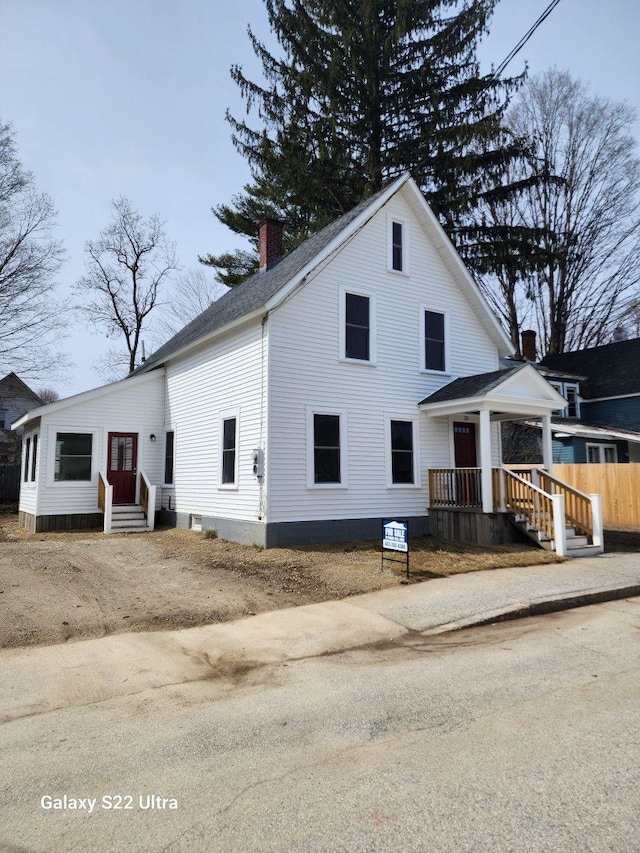 view of front of property featuring entry steps, fence, a chimney, and a shingled roof