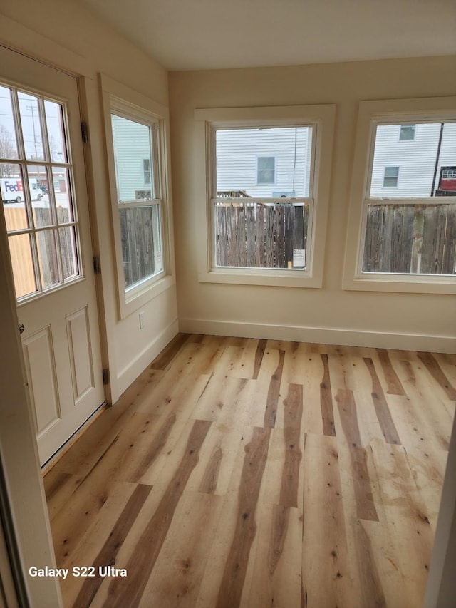 doorway to outside featuring baseboards, a wealth of natural light, and light wood-type flooring