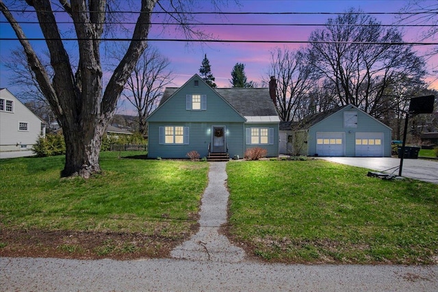 view of front facade with a garage, driveway, a yard, a chimney, and an outbuilding