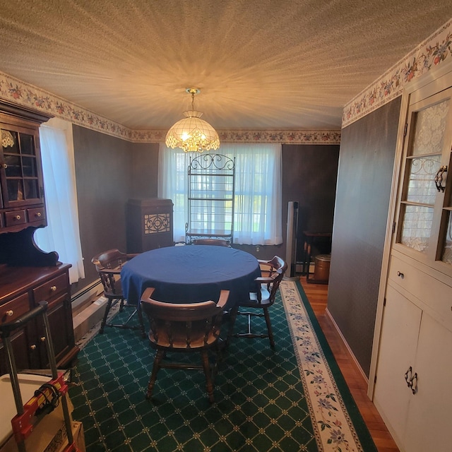 dining room featuring wood finished floors, a baseboard heating unit, and a notable chandelier