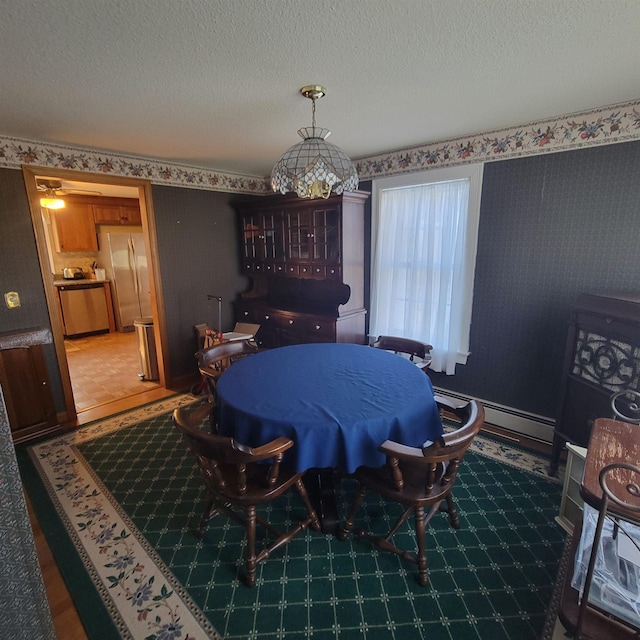 dining room with a baseboard heating unit, wallpapered walls, and a textured ceiling