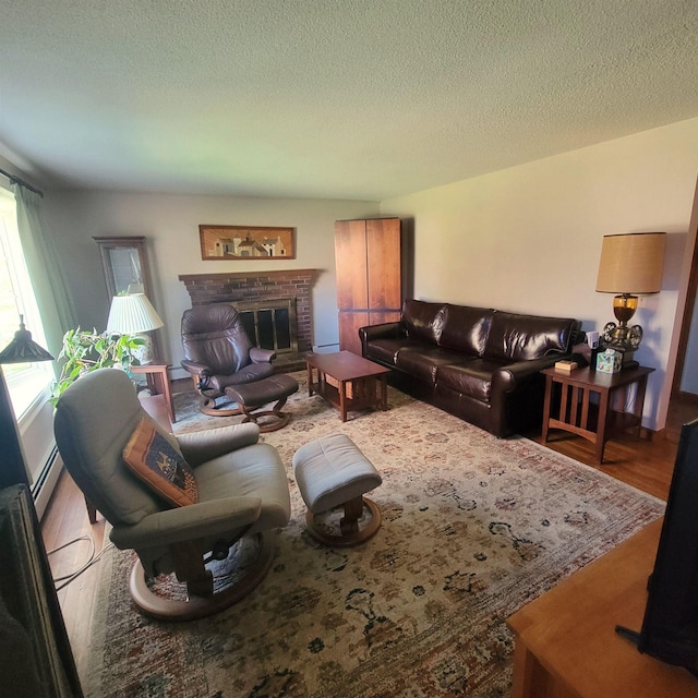 living area with a textured ceiling, a brick fireplace, and wood finished floors
