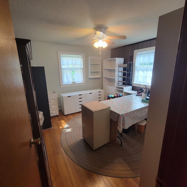 home office featuring light wood-style floors, a textured ceiling, and ceiling fan