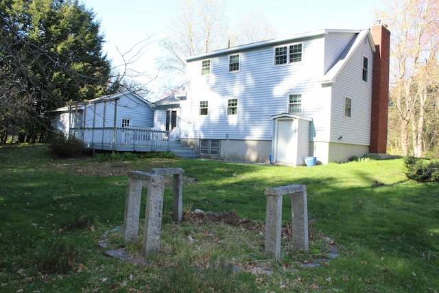 rear view of property with a lawn, a wooden deck, and a chimney