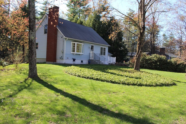 cape cod-style house with a chimney and a front yard
