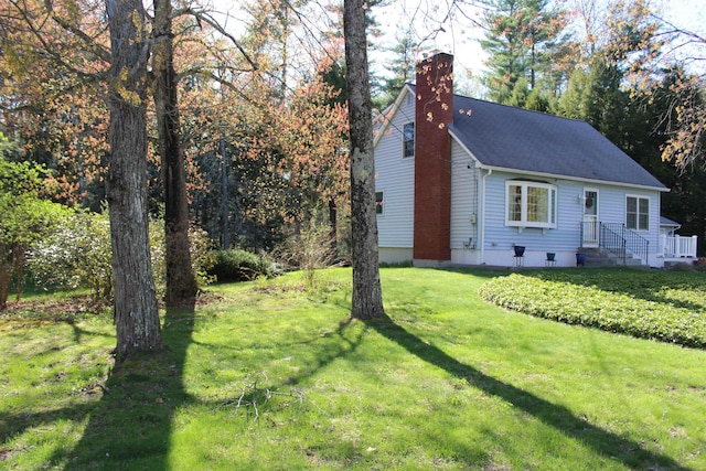 view of property exterior featuring a lawn, a chimney, and a shingled roof