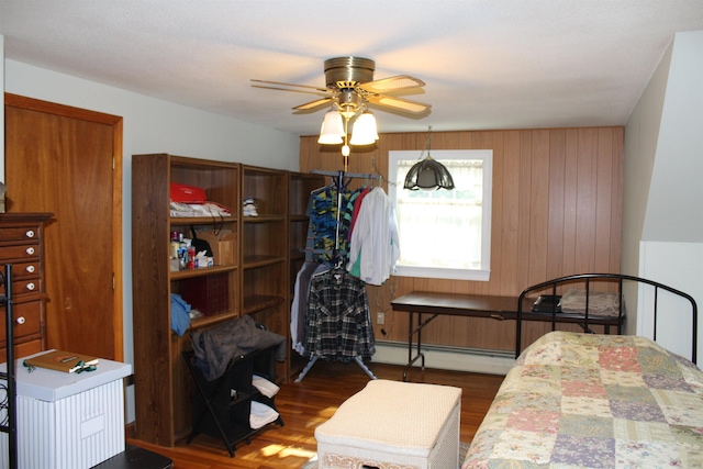 bedroom with a ceiling fan, a baseboard heating unit, and wood finished floors