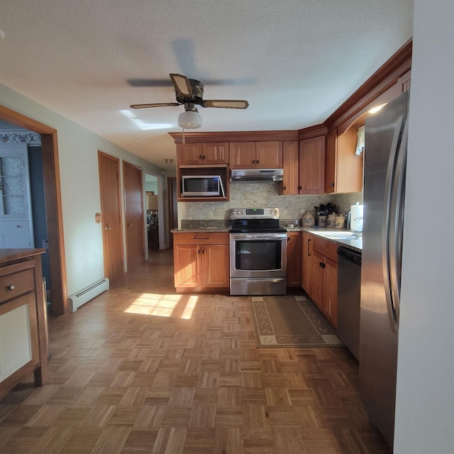 kitchen featuring ceiling fan, appliances with stainless steel finishes, tasteful backsplash, under cabinet range hood, and a baseboard heating unit