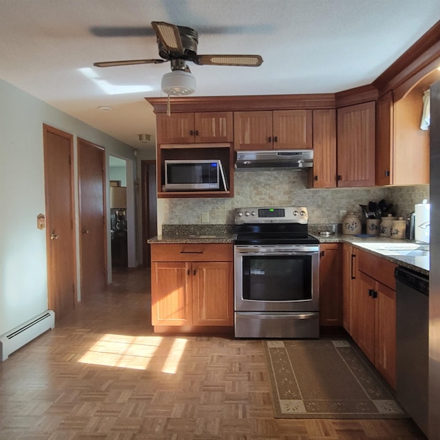 kitchen featuring ceiling fan, a baseboard heating unit, under cabinet range hood, tasteful backsplash, and appliances with stainless steel finishes