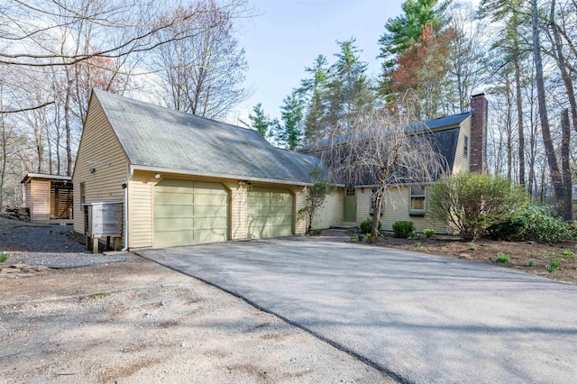 view of front of home featuring a chimney, an attached garage, and driveway