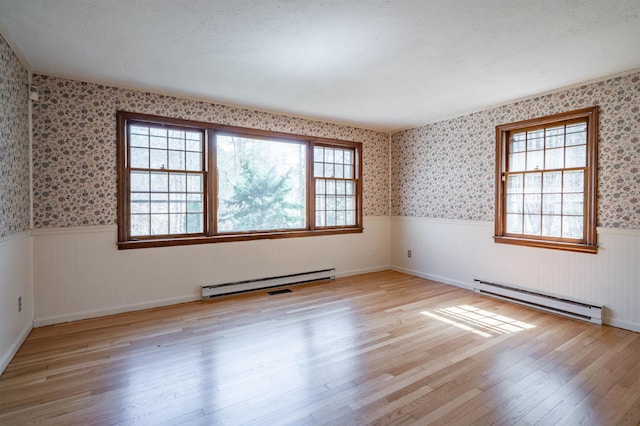unfurnished room with a baseboard radiator, wainscoting, wood finished floors, and wallpapered walls