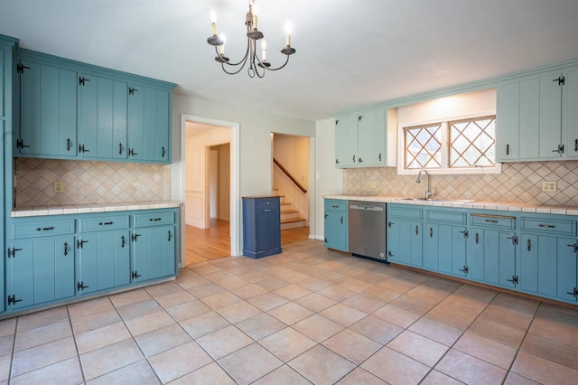 kitchen with decorative backsplash, blue cabinets, stainless steel dishwasher, a sink, and a chandelier