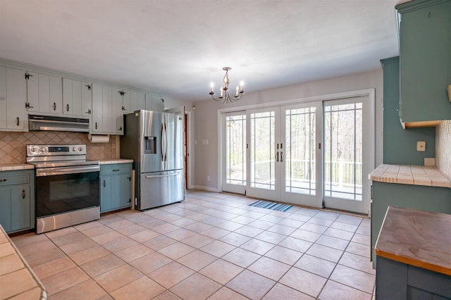 kitchen featuring under cabinet range hood, a chandelier, tasteful backsplash, light tile patterned floors, and stainless steel appliances