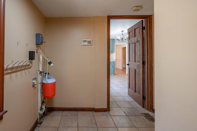 corridor with baseboards, a chandelier, light tile patterned floors, and visible vents