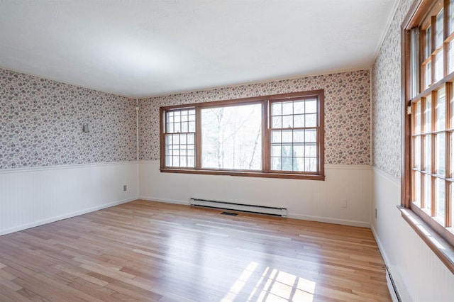 empty room with visible vents, wainscoting, a baseboard radiator, light wood finished floors, and wallpapered walls