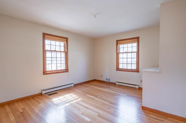 empty room featuring baseboards, a baseboard radiator, and light wood finished floors