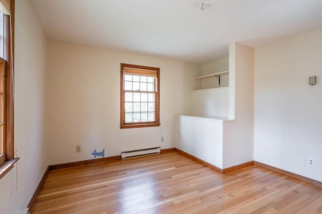 empty room with baseboards, a baseboard heating unit, and light wood-style flooring