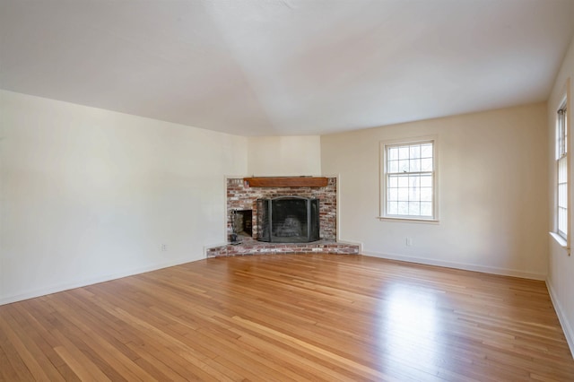 unfurnished living room featuring a healthy amount of sunlight, baseboards, and hardwood / wood-style floors