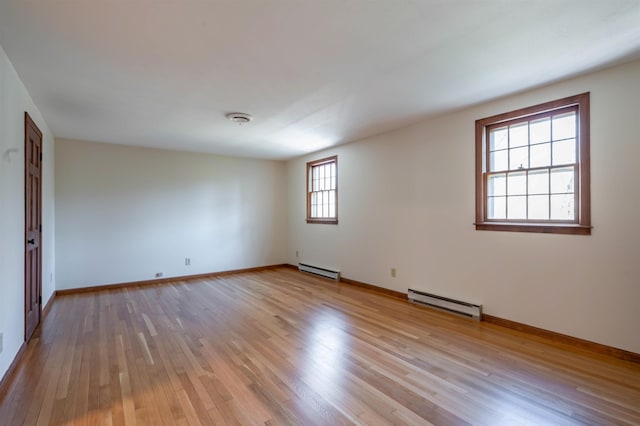 empty room with light wood-style floors, baseboards, and a baseboard heating unit